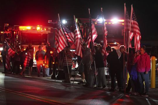 People hold American flags before a procession Wednesday, Sept. 17, 2025, in Spring Grove, Pa., after multiple police officers were shot and killed.People hold American flags before a procession Wednesday, Sept. 17, 2025, in Spring Grove, Pa., after multiple police officers were shot and killed.