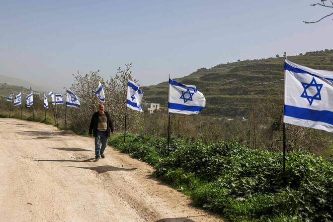 Palestinian man walks past a fence decorated with Israel flags installed by Jewish settlers in the northern Israel-occupied west bank | AFP