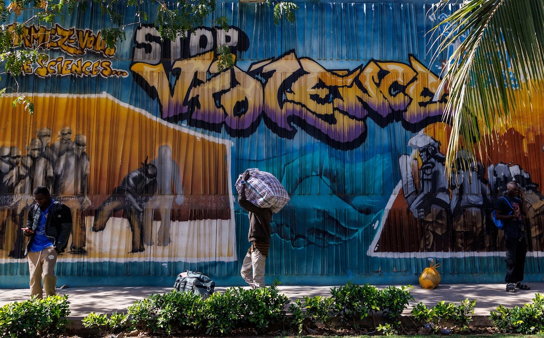 A student carries a bag with his belongings as he walks past a graffiti mural reading “Stop Violence” outside the Cheikh Anta Diop University campus that was closed today until further notice after clashes with security forces left one student dead during protests in which demonstrators have been demanding stipends and other financial support amid the government’s ongoing fiscal challenges in Dakar, Senegal, February 10, 2026. | REUTERS/Zohra Bensemra