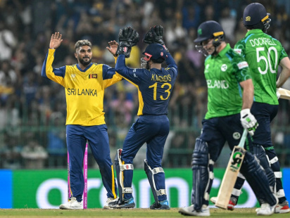 Sri Lanka's Wanindu Hasaranga (L) celebrates with teammate Kusal Mendis (2L) after taking the wicket of Ireland's Curtis Campher during the 2026 ICC Men's T20 Cricket World Cup group stage at the R Premadasa Stadium in Colombo on February 8, 2026. | AFO